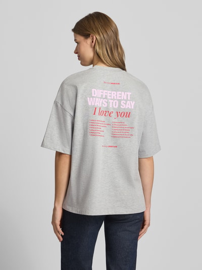 Kobiece modelka nosi damski t-shirt z bawełny w kolorze szarym z nadrukiem z logo, krój oversized, okrągły dekolt, model 'Lotte' od LeGer by Lena Gercke, długość tyłu w rozmiarze 36: 66 cm, widok całej sylwetki z tyłu.