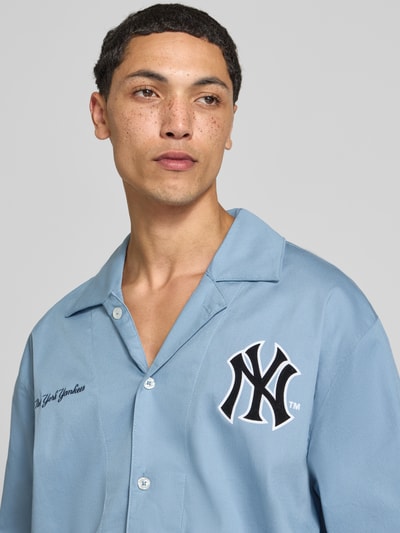 Männermodel trägt Relaxed Fit Freizeithemd aus Baumwoll-Mix von Champion, hellblau, Statement-Stitching, Reverskragen, Nahaufnahme Oberkörper.