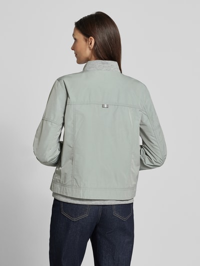 Frauenmodel trägt Jacke mit Zweiwege-Reißverschluss von Amber & June in Hellgrau, krój regular fit, stehend, Rückansicht, długość tyłu w rozmiarze 36: 56 cm, szerokość ramion w rozmiarze 36: 42 cm, szerokość w biuście w rozmiarze 36: 51 cm, długość rękawa w rozmiarze 36: 60 cm, naszywane kieszenie z suwakiem i kieszenie z zapięciem na guzik. Ganzkörperansicht Rückansicht.