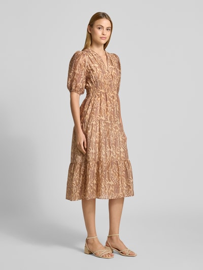 Frauenmodel trägt Midikleid aus Lyocell-Mix Modell 'Tanyssa' von Bash mit Allover-Paisley-Print, Tunika-Kragen, taillierte Passform, Halbarm, elastische Ärmelabschlüsse, dezente Beige- und Rosétöne, feine Musterstruktur, Ganzkörperansicht von vorne.