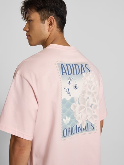 Männermodel trägt pastellrosafarbenes Relaxed Fit T-Shirt aus reiner Baumwolle Modell 'SUMMER GRAPHIC' von adidas Originals, Rückansicht. Herren T-Shirt von adidas Originals.