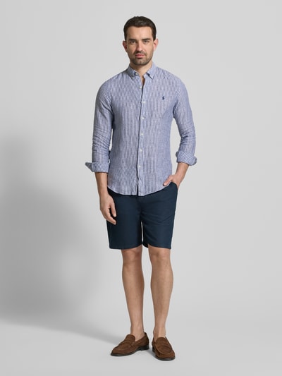 Männermodel draagt Slim Fit vrijetijdsoverhemd uit puur linnen van Polo Ralph Lauren in meerkleurige gestreepte look met button-downkraag, enkele knoopsluiting, langemouw met sportmanchet, afgeronde rompzoom, logodetail, achterpas met cacharelplooi, gevlamd garen. Ganzkörperansicht van voren.