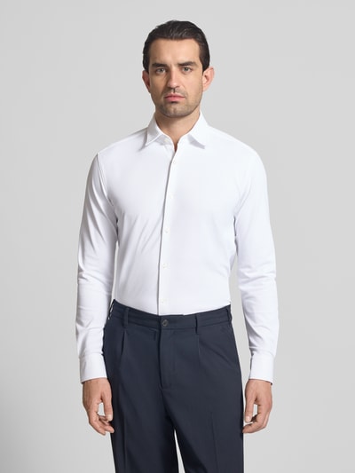 Männermodel trägt Slim Fit Businesshemd in Struktur-Optik Modell 'ERMO' von HUGO in Weiß, Kentkragen, Piqué-Material, Ganzkörperansicht von vorne.