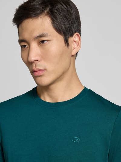 Mannelijk model draagt Regular Fit T-Shirt uit pure katoen van Tom Tailor in effen donkergroen met logo-stitching, ronde hals, korte mouw, Nahaufnahme bovenlichaam.
