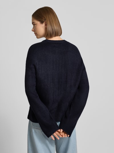 Frauenmodel trägt Relaxed Fit Pullover mit Rundhalsausschnitt Modell 'SIMONI' von ONLY in Dunkelblau und hellblaue Jeans, Ganzkörperansicht Rückansicht, Damen Pullover von ONLY.