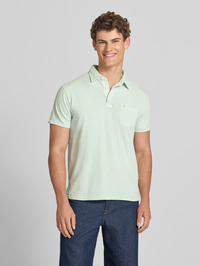 Männermodel trägt Slim Fit Poloshirt mit Brusttasche von Superdry, Baumwoll-Leinen-Mix, Knopfleiste, Rückenlänge 67 cm, Ganzkörperansicht von vorne.