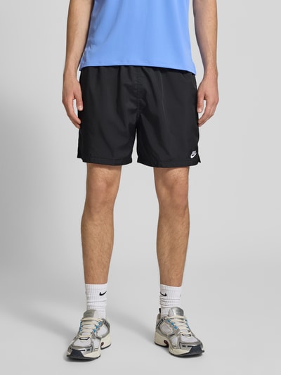 Männermodel trägt schwarze Shorts mit Label-Stitching und elastischem Bund von Nike, Regular-Fit, Tunnelzug, Ganzkörperansicht von vorne.