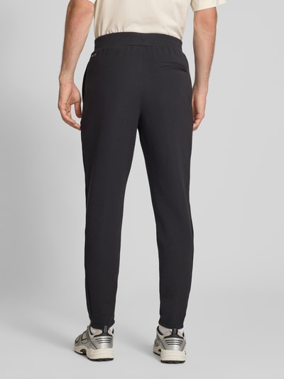 Männermodel trägt schwarze Regular Fit Sweatpants mit Lyocell-Anteil von PUMA PERFORMANCE, elastischer Bund, Rückansicht, Ganzkörperansicht