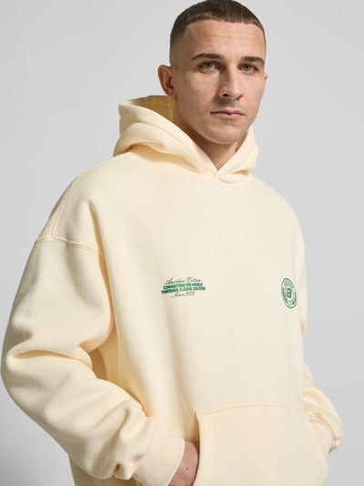 Männermodel trägt Hoodie mit Logo-Prints Modell 'Sunday Miles' von ANOTHER COTTON LAB, cremefarben, Baumwoll-Mix, Nahaufnahme Oberkörper.