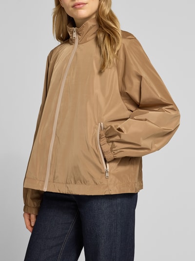 Frauenmodel trägt Jacke mit elastischen Abschlüssen und Stehkragen von Fuchs Schmitt, Reißverschluss, Raglanärmel, Gerade, Seitliche Reißverschlusstaschen, Rückenlänge 56 cm, Schulterbreite 38 cm, Brustweite 48 cm, Ärmellänge 43 cm, Beige, glatte Textur, Ganzkörperansicht von vorne.