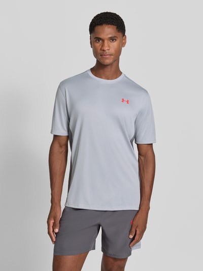 Männermodel trägt Regular Fit Sport-T-Shirt mit Label-Print von Under Armour in Hellgrau, glatte Struktur, Ganzkörperansicht von vorne. Herren Sport-T-Shirt von Under Armour.