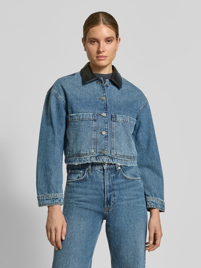 Vrouwenmodel draagt Cropped Jeansjacke aus reiner Baumwolle van Diesel in blauw met rechte vormen, gladde textuur, regular fit, knoopsluiting en opgestikte steekzakken, vooraanzicht van het hele lichaam.