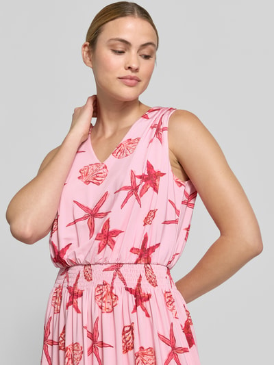 Frauenmodel trägt Midikleid mit Allover-Motiv-Print von Milano Italy in Rosa mit Rot, V-Ausschnitt, Smok-Detail, Nahaufnahme Oberkörper. Taillierte Passform, Rückenlänge bei Größe S: 117 cm, Ärmellänge bei Größe S: 47 cm.