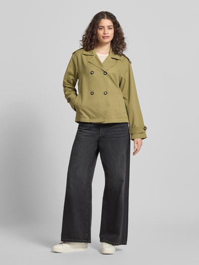 Frauenmodel trägt Regular Fit Trenchcoat-Jacke mit Reverskragen Modell 'HANNAH' von Only in Olive, Optik: Unifarben, Ganzkörperansicht von vorne. Passform: Regular-Fit, Verschluss: doppelreihige Knopfleiste, Applikation: Schulterriegel, Details: Rückenpasse, Ärmelform: Langarm, Taschen: seitliche Eingrifftaschen.