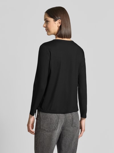 Frauenmodel trägt Regular Fit Bluse mit Brusttaschen von monari in Schwarz, mit Ziersteinbesatz, Tunika-Ausschnitt, langärmelig, Rückenansicht, Ganzkörperansicht Rückansicht.