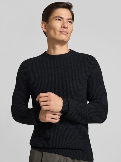 Männermodel trägt Strickpullover aus Kaschmir mit Rundhalsausschnitt von FTC Cashmere, grob gestrickt, dunkle Farbe, Nahaufnahme Oberkörper.
