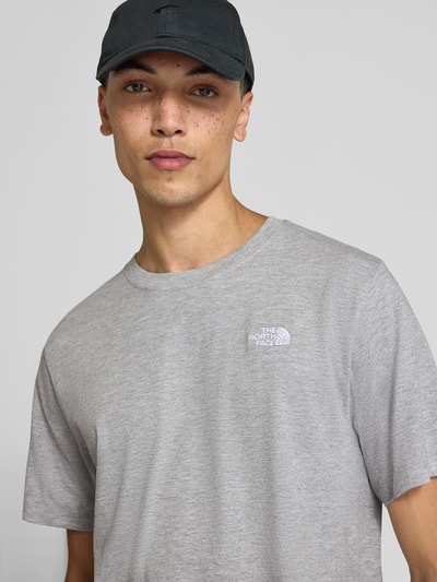 Männermodel trägt Regular Fit T-Shirt mit Rundhalsausschnitt Modell 'EVOLUTION' von The North Face in Hellgrau, Nahaufnahme Oberkörper. Herren T-Shirt, Label-Stitching, Rückenlänge bei Größe M 72 cm.