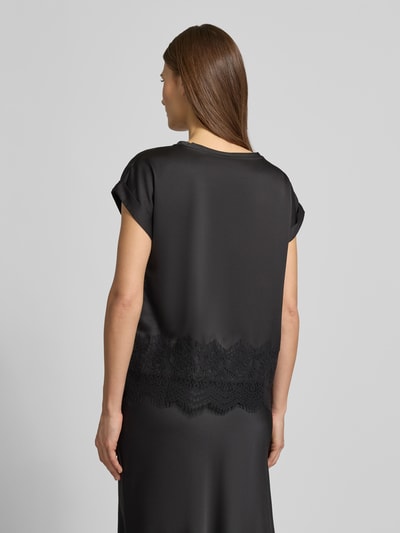 Frauenmodel trägt T-Shirt mit Rundhalsausschnitt Modell 'ELLETTE' von Vila, schwarzes Satin mit Spitzenbesatz, lockerer Schnitt, Ganzkörperansicht Rückansicht.