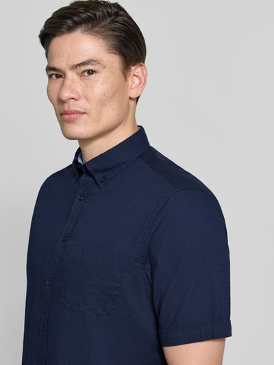 Männermodel trägt Regular Fit Freizeithemd mit Button-Down-Kragen von Christian Berg Men in Dunkelblau, Reine Baumwolle, Nahaufnahme Oberkörper. Rückenlänge bei Größe M: 81 cm, Schulterbreite 48 cm, Ärmellänge 26 cm, durchgängige Knopfleiste, kurzärmeliges Design.