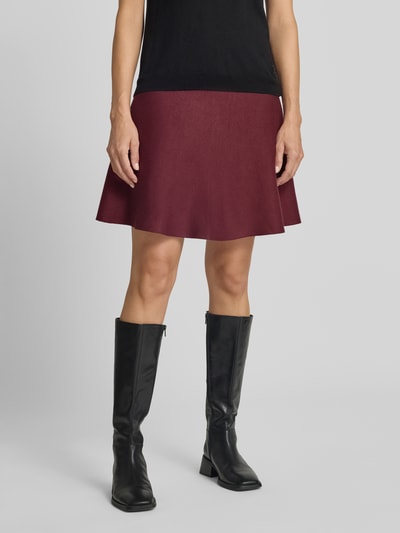 Vrouwenmodel draagt Ausgestellter Mini-Rock aus Viskose-Mix van Jake*s Collection in bordeauxrood, glad oppervlak, minirok, ganz lichaamsaanzicht van voren.