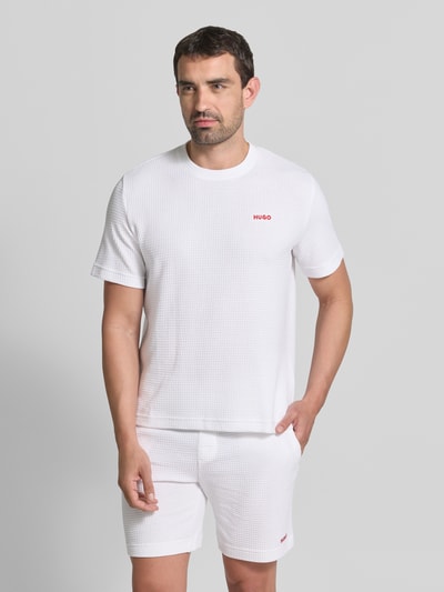 Męski model trägt Męski t-shirt aus bawełny-mix model 'AUSTIN' von HUGO, kolor biały, struktura prążkowana, Ganzkörperansicht von vorne.