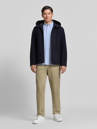 Męski model nosi Regular Fit Jacke aus Schurwoll-Mix od Armani Exchange, granatowy kolor, kaptur z tunelem, zamek błyskawiczny dwustronny, wpuszczane kieszenie, długość tyłu w rozmiarze M: 74 cm, szerokość ramion w rozmiarze M: 50 cm, szerokość klatki piersiowej w rozmiarze M: 61 cm, długość rękawów: 66 cm, widok całej sylwetki z przodu.
