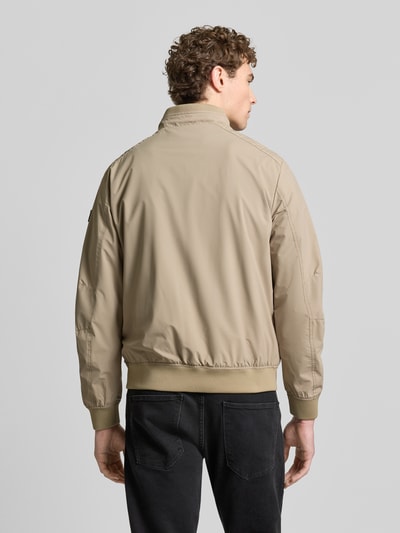 Męski model nosi Regular Fit Jacke mit Stehkragen von Lerros, beżowa, elastyczny materiał, detal logo, suwaki, widok całej sylwetki z tyłu