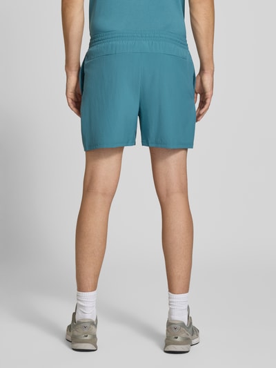Männermodel trägt Shorts mit elastischem Bund und Logo von New Balance in Blau, Regular Fit, Rückansicht Ganzkörperansicht.