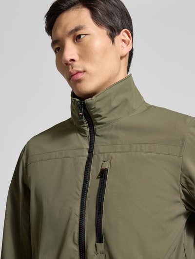 Männermodel trägt Comfort Fit Blouson mit geripptem Rumpfabschluss von Tom Tailor in Oliv, wasserabweisend, Nahaufnahme Oberkörper.