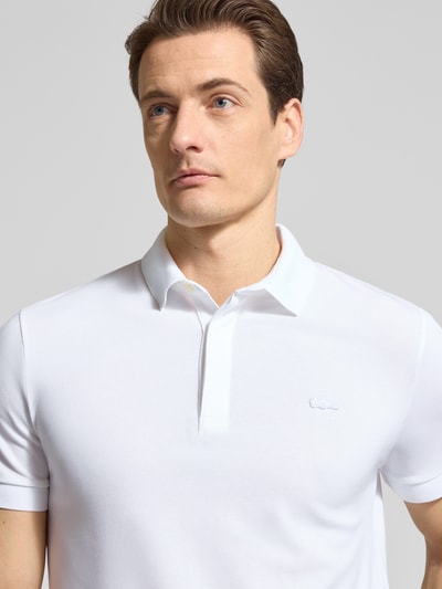 Męski model nosi Regular Fit Poloshirt aus Baumwoll-Mix von Lacoste, jednokolorowy, wyhaftowane logo, pika, mieszanka bawełny, nahaufnahme górnej części ciała.