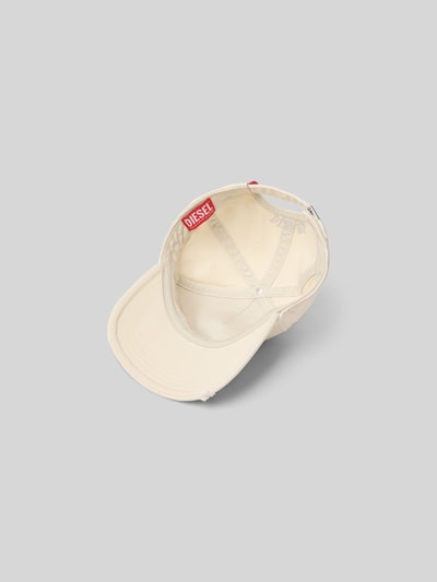 Produktfoto, Basecap mit Label-Detail von Diesel aus reiner Baumwolle in Beige, verstärkter Schirm, verstellbarer Verschluss, eingestickte Luftlöcher, rote Label-Applikation, glatte Textur.