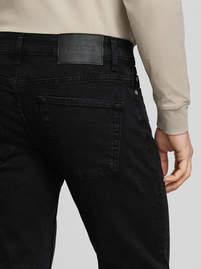 Männermodel trägt Slim Fit Jeans aus Baumwoll-Mix Modell 'LOOM' von Only & Sons in Schwarz, Label Patch, Detailaufnahme Rückansicht.