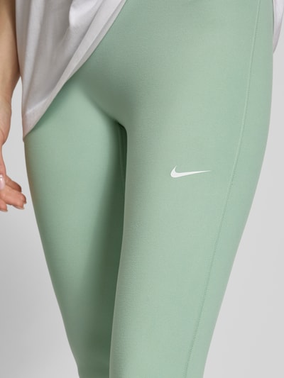 Frauenmodel trägt Leggings mit Logo-Print Modell 'One' von NIKE TRAINING in Grün, Material-Mix mit Stretch-Anteil, Slim-Fit, Nahaufnahme Oberschenkel.