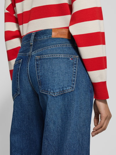 Frauenmodel trägt Wide Leg Jeans aus reiner Baumwolle Modell 'DNM NEW DOREEN 70 S' von Tommy Hilfiger, Denim-Optik, Label-Patch, Logo-Stitching, Nieten, 5-Pocket-Design, High-Waist, Ganzkörperansicht Rückansicht.