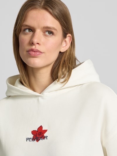 Vrouwenmodel draagt Oversized Hoodie mit Label-Stitching Modell 'MODRA' van Pegador in gebroken wit, katoenmix, labelstiksel en kangoeroezak, close-up bovenlichaam.