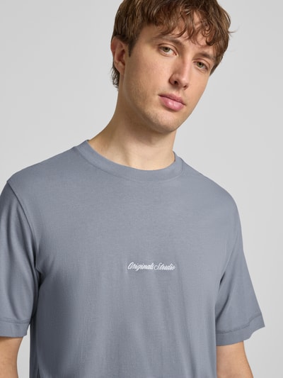 Męski model ma na sobie T-Shirt mit Label-Stitching Modell 'NORREBRO' od Jack & Jones, czysta bawełna, krój regular fit, szary kolor, okrągły dekolt, delikatna faktura, długość tyłu w rozmiarze M: 66 cm, widok na górną część ciała, z przodu