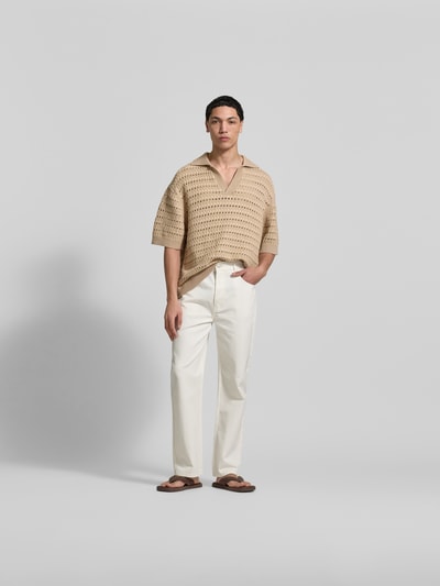 Männermodel trägt Relaxed Fit Poloshirt mit Viskose-Anteil von MAISON KITSUNÉ, Lochmuster, halbarm, beige, Ganzkörperansicht von vorne.