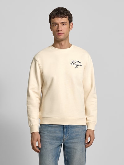 Mannelijk model draagt Sweatshirt met Label-Print van Scotch & Soda, crèmekleurige katoen, regular fit, ronde hals, volledige voorkant.