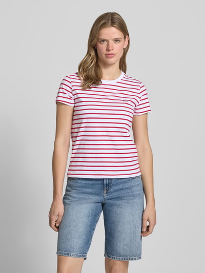 Frauenmodel trägt Regular Fit T-Shirt aus reiner Baumwolle von Levi's® mit rot-weißen Streifen, Rundhals, Kurzarm, Ganzkörperansicht von vorne.