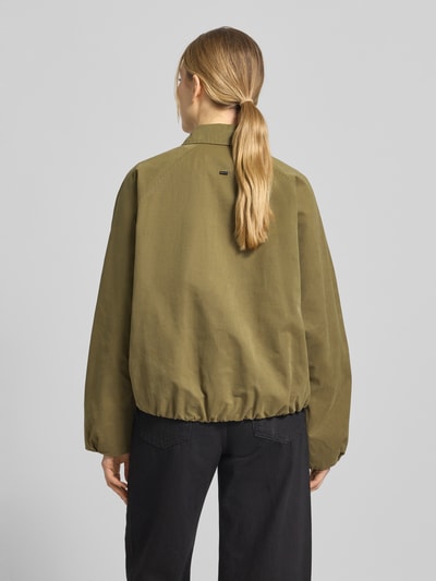 Frauenmodel trägt Blouson aus reiner Baumwolle von WHITE LABEL in Oliv mit Umlegekragen, lockerer Passform, Eingrifftaschen, Rückenlänge 62 cm, Schulterbreite 40 cm, Brustweite 64 cm, Ärmellänge 65 cm, Ganzkörperansicht Rückansicht.