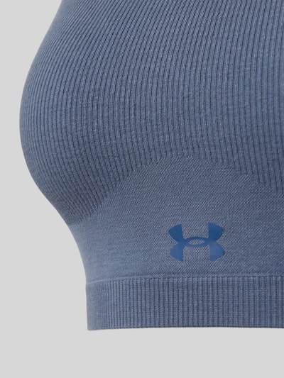 Frauenmodel trägt Sport-BH aus Baumwoll-Mix von Under Armour in Blau mit gerippter Struktur, Nahaufnahme Oberkörper. Damen Sport-BH von Under Armour.