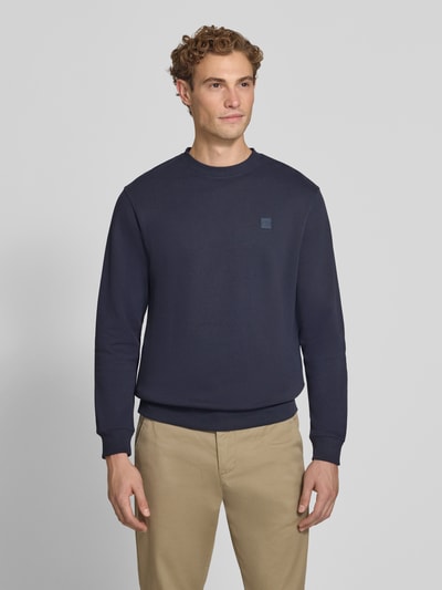 Männermodel trägt Regular Fit Sweatshirt aus reiner Baumwolle mit Label-Patch von Scotch & Soda in Dunkelblau, Nahaufnahme Oberkörper. Rückenlänge 70 cm, Ärmellänge 66 cm, elastische Abschlüsse.