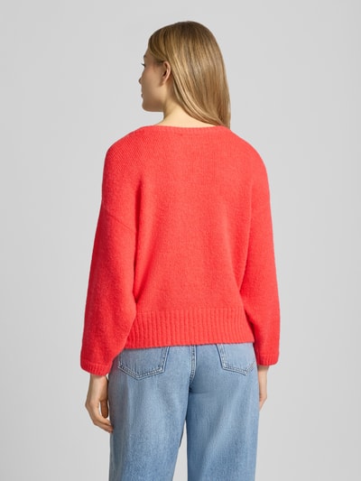 Frauenmodel trägt Relaxed Fit Pullover mit Alpaka-Anteil Modell 'East' von American Vintage, rote Strick-Optik, Statement-Detail, U-Boot-Ausschnitt, Elastischer-Material-Mix, Elastische Abschlüsse, Rückenlänge 42 cm, Ärmellänge 42 cm, Damen Pullover, Ganzkörperansicht Rückansicht.