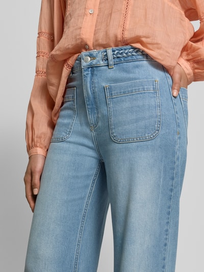 Frauenmodel trägt Straight Fit Jeans mit Eingrifftaschen von JAKE*S STUDIO WOMAN in Hellblau, sichtbarer Zopfmuster-Gürtel, Nahaufnahme Oberkörper.