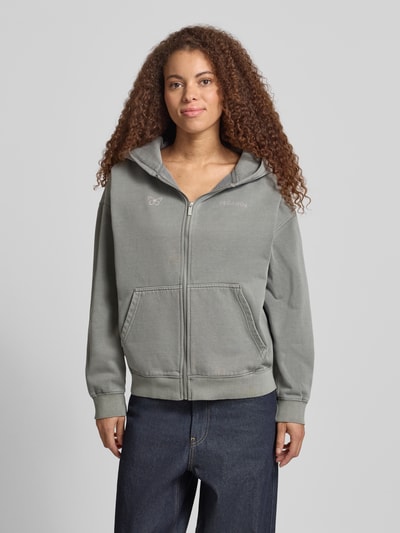 Modelka kobieca ma na sobie Oversized Sweatjacke mit Känguru-Tasche Modell 'NIVELLES' od Pegador, bawełniany melanż, zamek, logo, szare odcienie, kieszeń kangurka, przód, bawełniany miks, Ganzkörperansicht von vorne.