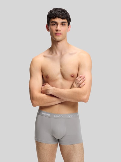 Männermodel trägt Slim Fit Trunks aus Baumwoll-Mix im 3er-Pack Modell 'PACK' von HUGO in Optik: Unifarben, Nahaufnahme Oberkörper. Materialverarbeitung: Stretch-Jersey, Applikation: Label-Schriftzug, Bundabschluss: Elastisch, Multipack: 3er-Pack.