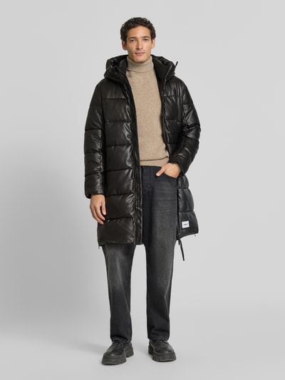 Männermodel trägt Regular Fit Mantel in Stepp-Optik Modell 'EMMET' von khujo, schwarze Farbe, glatte Struktur, Ganzkörperansicht von vorne.
