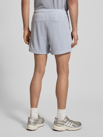 Männermodel trägt Shorts mit Label-Print von adidas Training in Hellgrau mit Lockerer-Schnitt und elastischem Bund, Ganzkörperansicht Rückansicht.