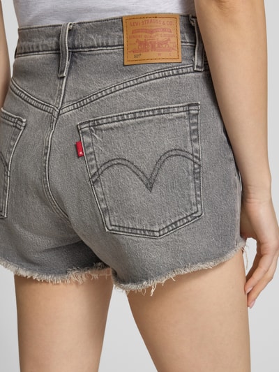 Frauenmodel trägt Regular Fit Jeansshorts aus Baumwoll-Mix Modell '501®' von Levi's®, graues Denim mit Label Patch und Fransen, Nahaufnahme Rückansicht.