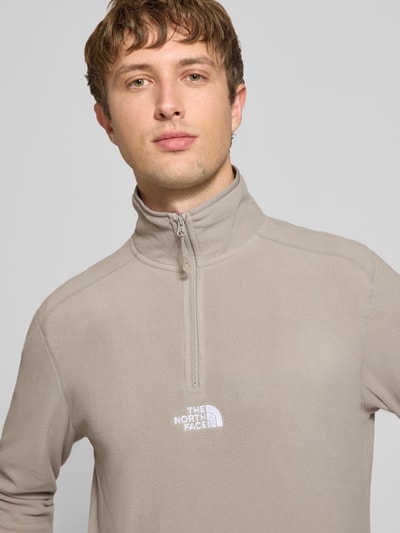 Männermodel trägt Fleecepullover mit Label-Stitching von The North Face in Beige mit Stehkragen und Reißverschluss, Nahaufnahme Oberkörper, Regular Fit